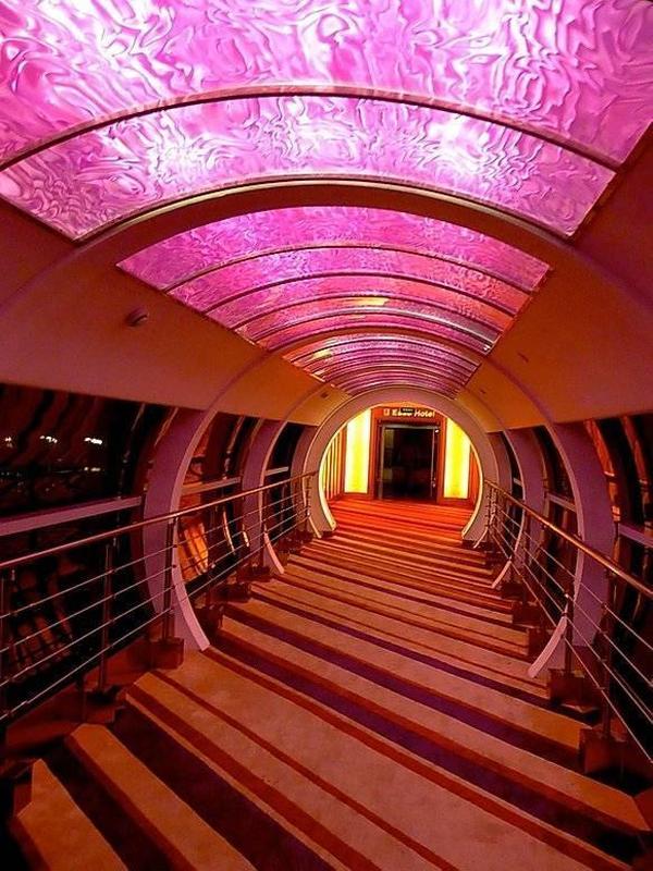 In einem Gebäudeverbindungsgang wurden Acryl-Designstrukturplatten mit IC / Display und LED-Leuchtmittel hinterleuchtet. Die tunnelartige Architektur bekommt durch die leuchtende glänzende Struktur der Acrylscheibe einen futuristischen Eindruck.