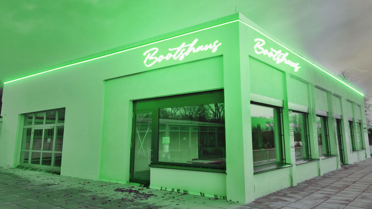 Das Gebäude bekommt durch sein Logo im Neon-Design einen Vintage-Charakter an der Aussenfassade. Eine umlaufende Konturbeleuchtung mit der gleichen Lichtfarbe wie vom Sign-Logo, gibt den Bootshaus ein Gesamtbild. Das LED-Farblicht in grün, beleuchtet das gesamte Gebäude. Durch die Architekturbeleuchtung im Neon-Design wirkt das Bootshaus schon vom weiten wie ein Blickfang.