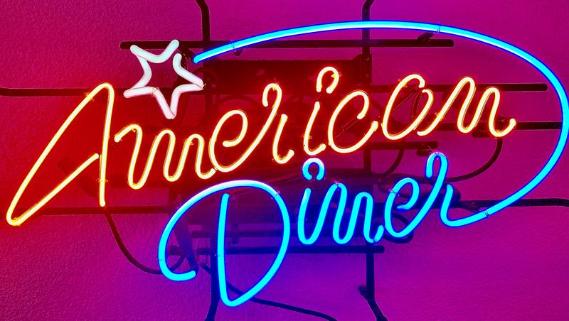 Durch den bunten Neon-Glas Schriftzug bekommt ein Diner-Restaurant das passende Erscheinungsbild. Der Durchmesser der Neon-Glas-Rohre ist 12mm. Bei dem rot leuchtenden „American“ handelt es sich um Klarglas, durch das der rote Leuchtstoff gepumpt wird.