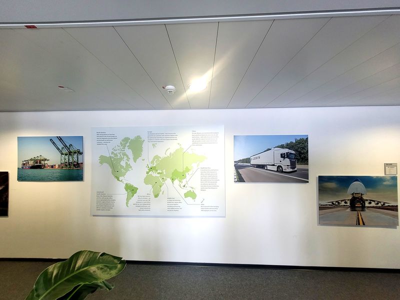 Wandgestaltung-Logwin Wandgestaltung bei Logwin mit großformatigen Bildern auf Alu-Dibond gedruckt, inklusive Weltkarte der Logistikstandorte, Transportmotive und professioneller Montage. Alu-Dibond Drucke bieten eine Reflexionsfreie Oberfläche. Dank modernster Drucktechnologie spiegeln sich Deckenstrahler nicht störend im Motiv.