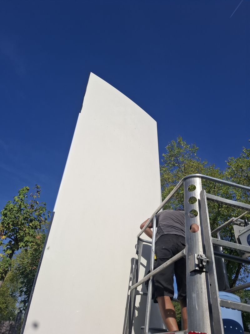 Montage für den Pylon erfolgte mit Hubarbeitsbühne, sodass die großformatigen Folien passgenau auf den gebogenen Pylonflächen verarbeitet werden konnten. Gerade bei dieser Höhe und den gewölbten Flächen kommt es auf millimetergenaue Ausrichtung und eine blasenfreie Verklebung an.