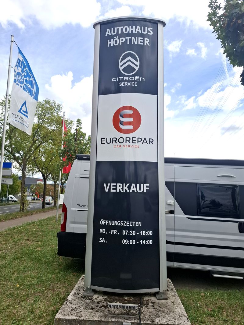 Pylon-Neubeschriftung Autohaus Höptner-Folienkaschierung Für das Autohaus Höptner wurde ein bestehender, rund 4 Meter hoher Werbepylon durch eine umfassende Folienkaschierung optisch neu gestaltet. Durch die Kombination aus Flächenfolierung, Logoapplikationen und geplotteten Schriftzügen konnte der vorhandene Werbepylon umfassend modernisiert werden.Ziel war es, die vorhandene Werbeanlage an das aktuelle Erscheinungsbild des Autohauses und der darauf präsentierten Marken anzupassen die