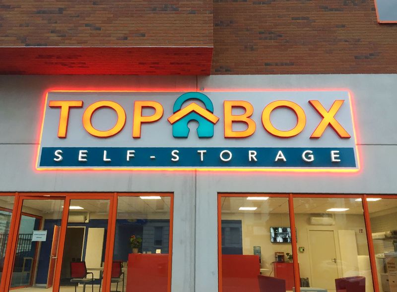 Auf einer hinterleuchteten Acrylplatte leuchten die Leuchtbuchstaben des Logos sowie der Schriftzug nach vorne. Die Vollrelief-Buchstaben mit transluzenter Frontseiten aus Acrylglas sind im Dunkel gut lesbar und werden durch die Rückbeleuchtung der Trägerplatte optisch besonders eingerahmt.  Die Leuchtschrift mit dem Firmenlogo an der Fassade strahlt effektvoll über den Eingang.