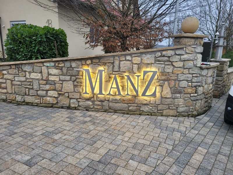 Der Schriftzug Weingut Manz ist mit Abstandhalter an der Mauer montiert, so das die Edelstahl-Buchstaben mit der Rückbeleuchtung einen Lichtschatten werfen. Durch das Reflexionslicht, hebt sich der Schriftzug Manz optisch ab und gibt eine atmosphärische Beleuchtung.







