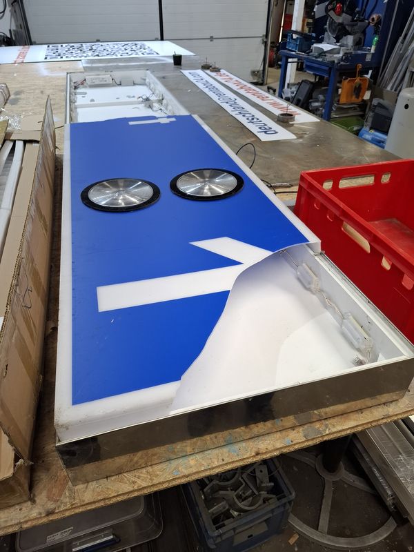 Leuchtkasten-Reparatur nach Bruchschaden: Dieses Werkstatt-Foto dokumentiert die Instandsetzung einer LED-Lichtwerbeanlage, bei der die transluzente Acrylscheibe mit der beschädigten Plotterfolie fachgerecht erneuert wird. Diese Beschilderung wurde Demontiert und die LED-Technik überprüft. 