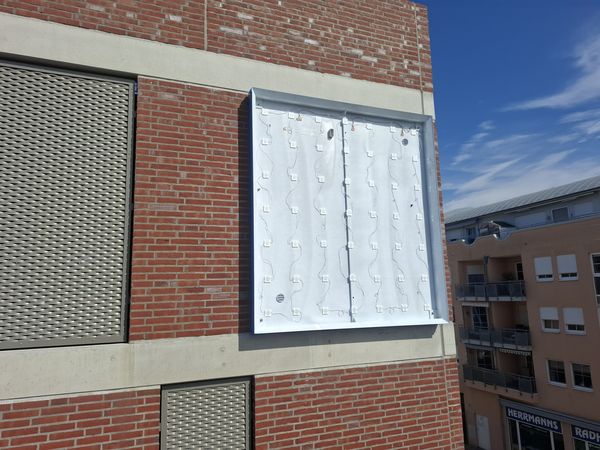 Geöffneter Leuchtkasten mit sichtbar angeordneten LED-Modulen und elektrischer Verkabelung. Die Aufnahme zeigt die technische Ausführung und die gleichmäßige Verteilung der LED-Beleuchtung innerhalb des Leuchtkastens. In 10 Meter Höhe mittels Steigers, wird somit der Kastenrahmen montiert und die Elektronik mit dem Transformator angeschlossen.